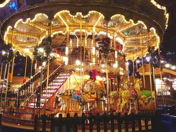 Illuminated carousel in amusement park at night