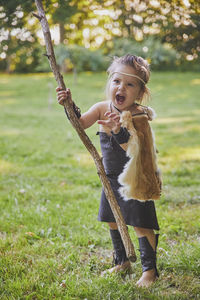 Cute baby dressed in the clothes of primitive people with combat staff