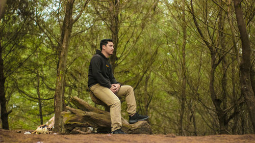 Full length of young man sitting in forest