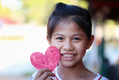 Close-up of young woman holding heart shape