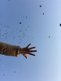 Low angle view of woman flying against clear blue sky