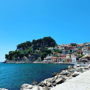 Scenic view of sea by buildings against clear blue sky