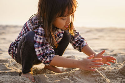 Full length of girl playing with sand at beach