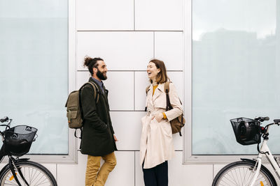 Man and woman with e-bikes standing at a building talking