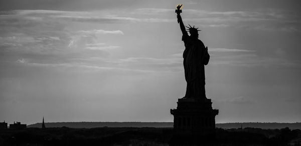 Low angle view of statue of liberty against cloudy sky