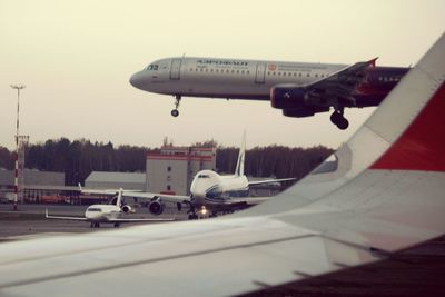 Airplane flying over airport runway against sky