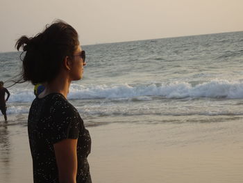 Woman standing at beach against sky