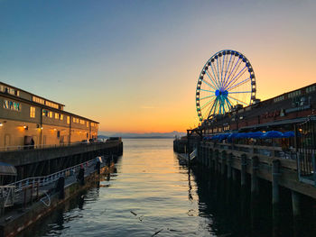 Ferris wheel in seattle washington behind wharf buildings at sunset