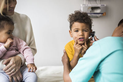 Portrait of boy making faces during ear examination by female doctor in clinic