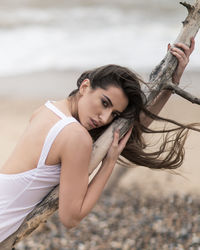 Portrait of young woman holding wood at beach