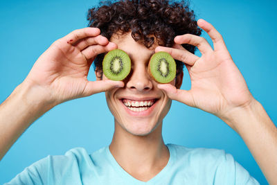 Portrait of smiling young woman holding apple against blue background