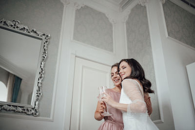 Bridesmaid and bride holding champagne flute