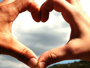 Close-up of hands holding heart shape against sky