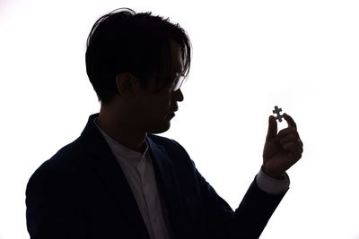 Portrait of man holding eyeglasses against white background