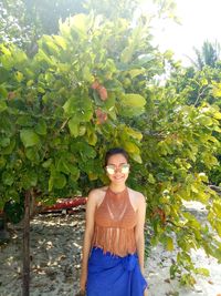 Portrait of a smiling young woman standing against plants