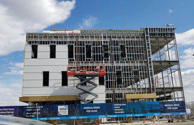 Low angle view of crane by building against sky