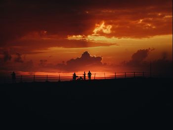 Silhouette people on beach against sky during sunset