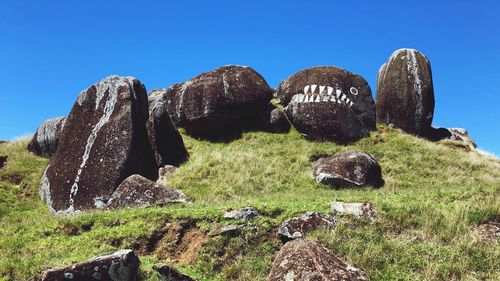 Panoramic shot of rocks on field against clear blue sky