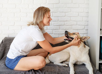 Young woman with dog sitting on sofa