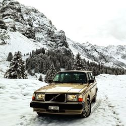 Vintage car on snow covered mountain against sky