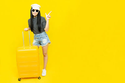 Woman holding umbrella against yellow background