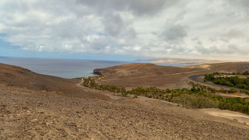 Scenic view of road by sea against sky