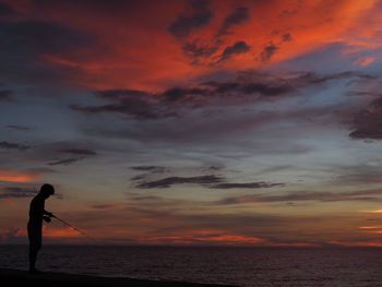 Silhouette of man photographing sunset