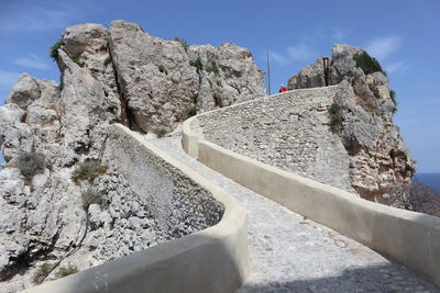 Rock formations by road against sky