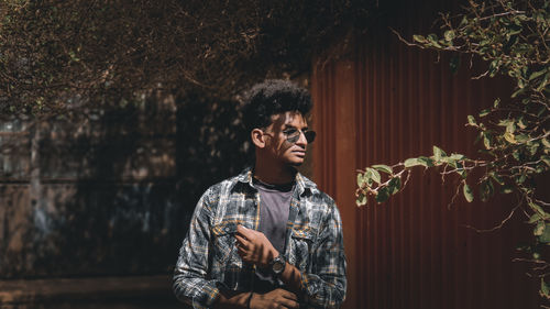 Portrait of young man looking away against plants