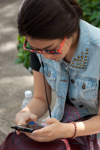 Woman using phone while sitting on retaining wall