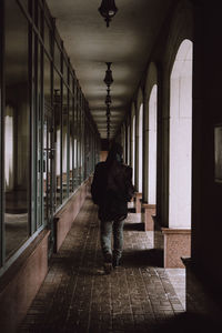 Rear view of people walking in corridor of shadows 