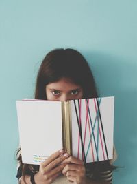 Portrait of girl with book against turquoise background