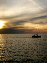 Sailboat sailing on sea against sky during sunset