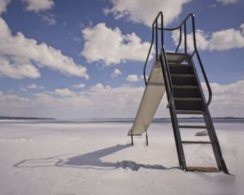 Empty deck chairs on beach against sky