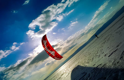 Low angle view of parachute over sand against sky