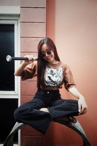 Young woman sitting against wall