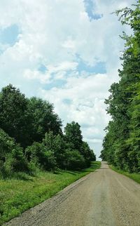 Empty road amidst trees against sky