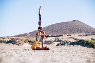 Man and woman exercising on land against sky