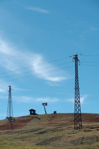 Low angle view of electricity pylon on field against sky