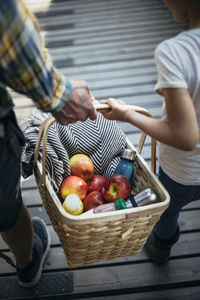 Father and daughter holding picnic basket full of apples on footbridge