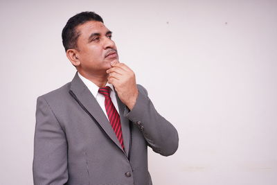 Young man looking away against white background