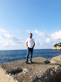 Portrait of man standing on rock against sea