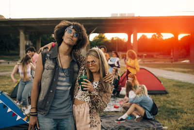 Fashionable friends with people in background at music event