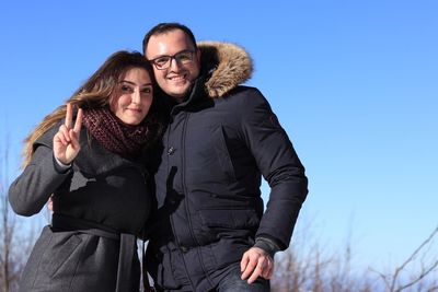 Portrait of couple wearing warm clothing against clear blue sky