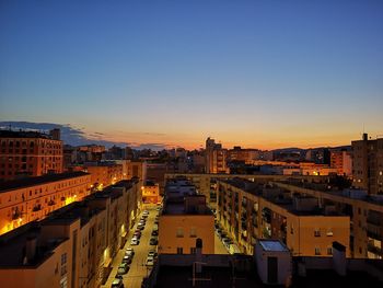 High angle view of illuminated buildings against clear sky during sunset