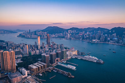 Drone shot of cityscape with sea against sky during sunset