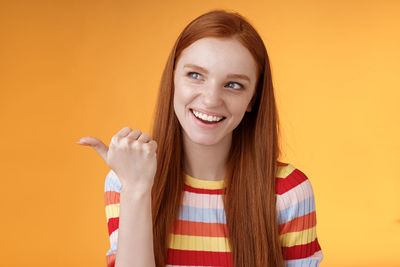 Portrait of a smiling young woman over yellow background