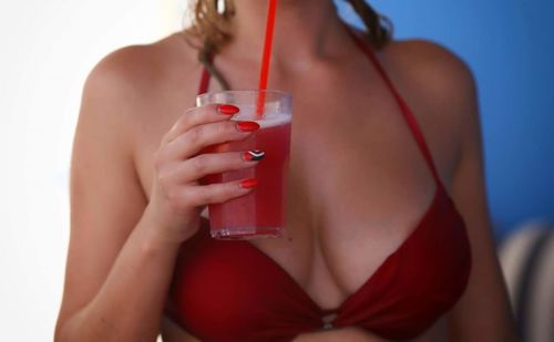 Midsection of bikini woman holding drink