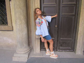 Full length of woman standing at entrance of building