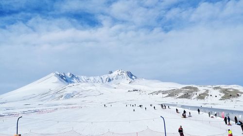 Group of people on snowcapped mountain against sky